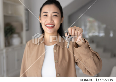 Closeup of smiling Vietnamese woman holds up set of keys 135700449