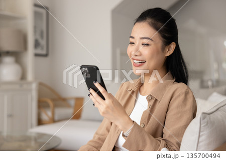 Happy woman engaged in remote digital communication using modern smartphone 135700494