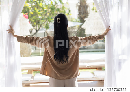Woman opening curtains, admire summer terrace with beautiful nature view Woman opening curtains, admire summer terrace with beautiful nature view 135700531