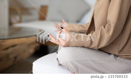 Close up cropped shot of woman doing meditation seated cross-legged 135700533