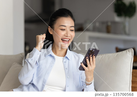 Happy Asian woman read great news on smartphone 135700568