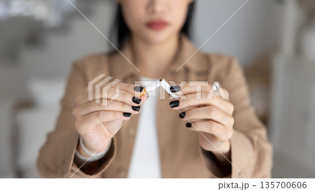 Close up woman hands holding broken cigarette Close up woman hands holding broken cigarette 135700606