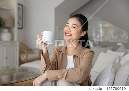 Woman relaxing on sofa with cup of morning tea Woman relaxing on sofa with cup of morning tea 135700610