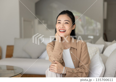 Asian woman sitting on comfortable couch in contemporary living room 135700611