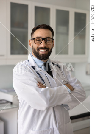 Cheerful young Hispanic doctor man posing for professional vertical portrait Cheerful young Hispanic doctor man posing for professional vertical portrait 135700703