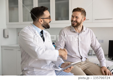Happy male doctor and patient shaking hands 135700724