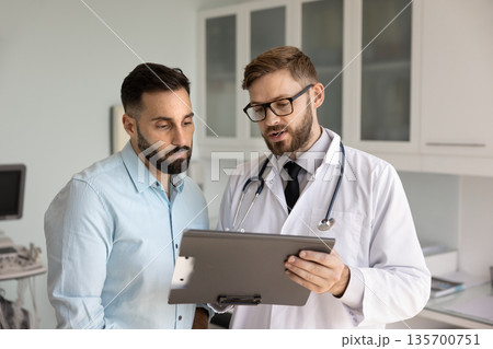Young medical practitioner man explaining checkup results to patient Young medical practitioner man explaining checkup results to patient 135700751