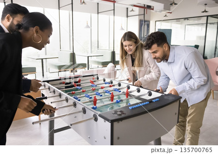 Joyful multiethnic workmates colleagues play foosball match divided into teams 135700765