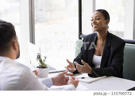 Smiling young businesswoman hold casual conversation with partners in cafe 135700772