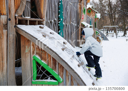 Child Climbing Snowy Playground Structure in Winter Park Child Climbing Snowy Playground Structure in Winter Park 135700800