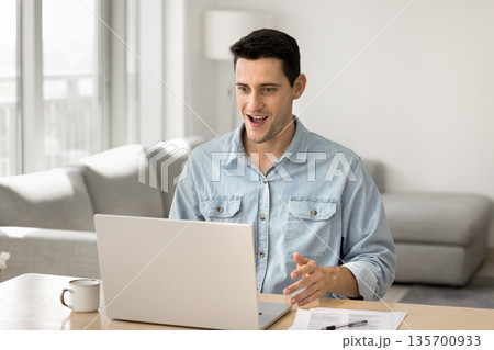 Overjoyed young male freelancer scream wow looking on notebook screen Overjoyed young male freelancer scream wow looking on notebook screen 135700933