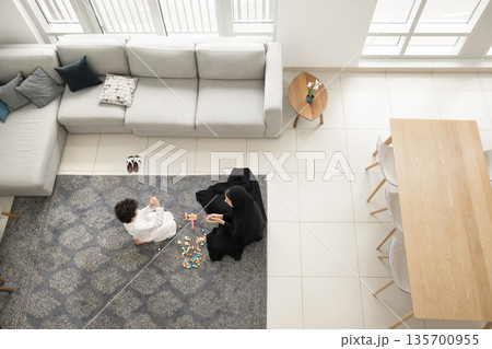 Happy Arabian mother little son constructing from blocks on carpet 135700955