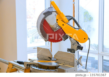 Table saw sits in saw has circular blade ready for cutting wood, tools materials surround area busy work environment. Table saw sits in saw has circular blade ready for cutting wood, tools materials surround area busy work environment. 135701367