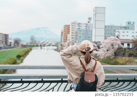 Woman tourist sightseeing Iwate mountain and Kitakami river with flowers in Spring, happy traveler travel in Morioka city, Iwate prefecture, Japan. famous Landmark Travel and Vacation destination Woman tourist sightseeing Iwate mountain and Kitakami river with flowers in Spring, happy traveler travel in Morioka city, Iwate prefecture, Japan. famous Landmark Travel and Vacation destination 135702255