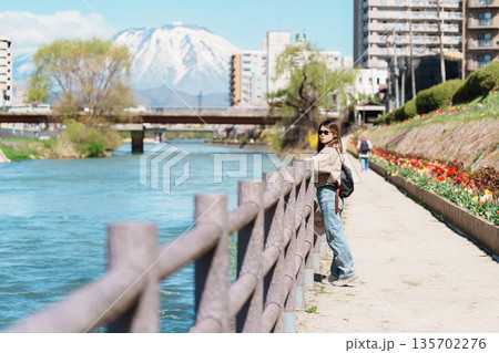 Woman tourist sightseeing Iwate mountain and Kitakami river with flowers in Spring, happy traveler travel in Morioka city, Iwate prefecture, Japan. famous Landmark Travel and Vacation destination 135702276