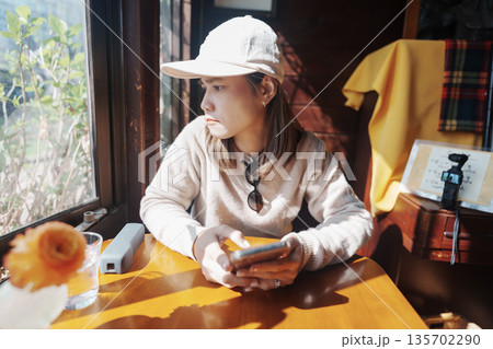 Young Asian woman using smartphone during relaxing in coffee cafe shop. Have a Nice day concept Young Asian woman using smartphone during relaxing in coffee cafe shop. Have a Nice day concept 135702290