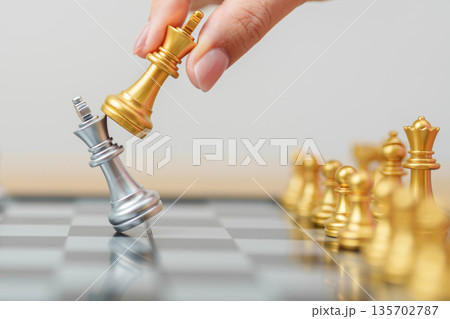 hand moving gold Chess King figure and Checkmate opponent during chessboard competition. Strategy, Success, management, business planning, win, disruption, Trade war and leadership concept 135702787