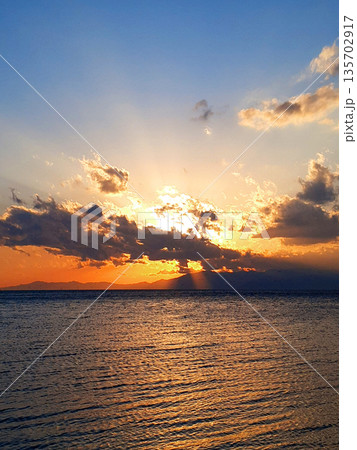神々しい光の筋 琵琶湖の水平線に沈む夕日と薄明光線が作り出す神秘的な風景 神々しい光の筋 琵琶湖の水平線に沈む夕日と薄明光線が作り出す神秘的な風景 135702917