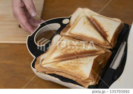 ホットサンドメーカーでホットサンドを作る手元 135703092