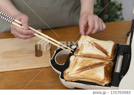 ホットサンドメーカーでホットサンドを作る手元 135703093