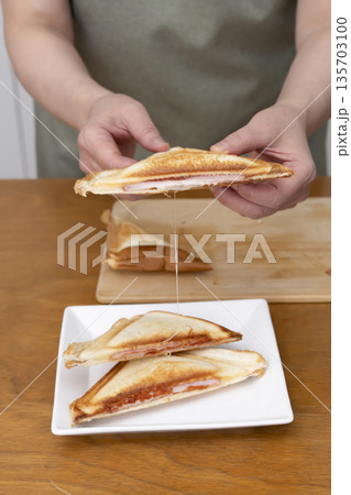 ホットサンドメーカーでホットサンドを作る手元 ホットサンドメーカーでホットサンドを作る手元 135703100