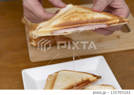ホットサンドメーカーでホットサンドを作る手元 135703101