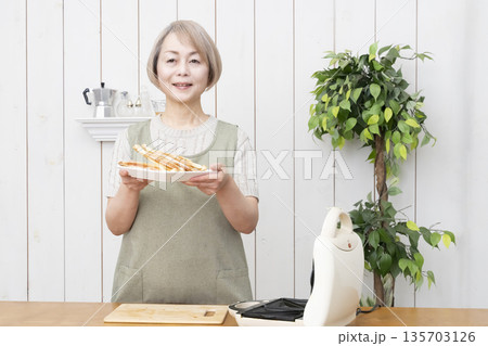 ホットサンドメーカーでホットサンドを作るシニア女性 135703126