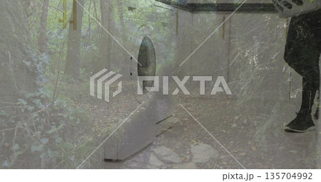 Displaying washer door overlaying woodland trail, with male wearing boots holding laundry basket 135704992