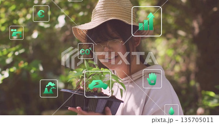 Chinese girl wearing straw hat and round glasses holding seedling tray in garden, with green icons Chinese girl wearing straw hat and round glasses holding seedling tray in garden, with green icons 135705011