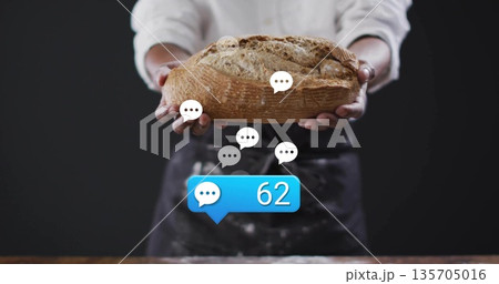Holding artisanal loaf, baker wearing apron in bakery, displaying chat bubbles and comment count 62 Holding artisanal loaf, baker wearing apron in bakery, displaying chat bubbles and comment count 62 135705016