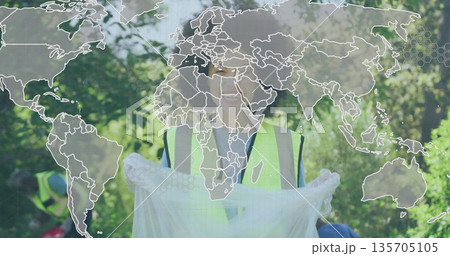 Collecting volunteer holding white bag in wooded park, wearing neon vests gloves, with map overlay 135705105