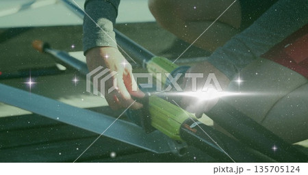 Securing athlete fastening carbon-fiber oars into oarlocks on dock, wearing grey top and red shorts Securing athlete fastening carbon-fiber oars into oarlocks on dock, wearing grey top and red shorts 135705124