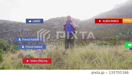 Surveying hiker carrying backpack wearing blue puffer vest on grassy hill, with social media icons Surveying hiker carrying backpack wearing blue puffer vest on grassy hill, with social media icons 135705166