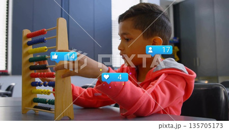 Counting boy wearing red sweatshirt moving beads on wooden abacus in classroom, with overlay icons Counting boy wearing red sweatshirt moving beads on wooden abacus in classroom, with overlay icons 135705173