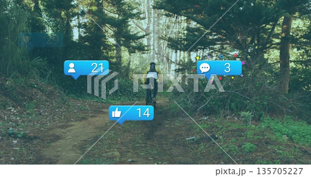 Riding mid-adult cyclist in helmet pedaling dirt trail through forest, with social media overlays Riding mid-adult cyclist in helmet pedaling dirt trail through forest, with social media overlays 135705227