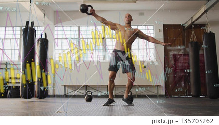 Swinging kettlebell shirtless athlete performing exercise in gym with punching bags, chart overlay 135705262