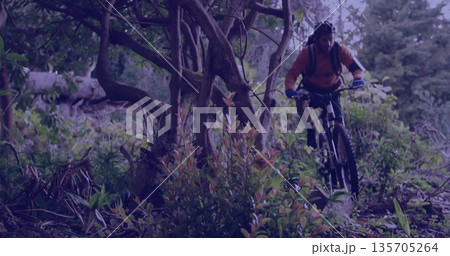 Riding mountain biker wearing orange jersey on forest trail with water pack and helmet, copy space 135705264