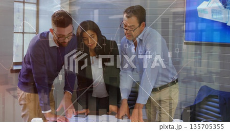 Analyzing team reviewing printed reports and discussing data at conference table, chart overlay 135705355
