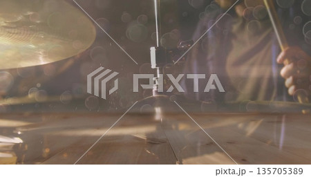 Striking drummer wearing dark long-sleeve shirt hitting hi-hat with drumstick on wooden platform 135705389