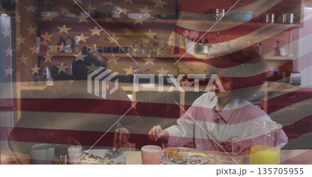 Sharing breakfast couple sitting at wooden kitchen table, with eggs, toast and US flag overlay 135705955