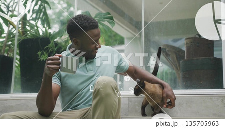 Sitting man holding mug, stroking cat by glass wall floating financial overlay, copy space Sitting man holding mug, stroking cat by glass wall floating financial overlay, copy space 135705963