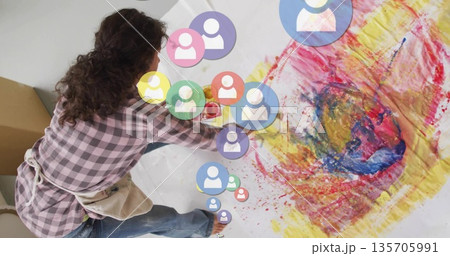 Artist wearing apron kneeling and painting on paper in studio with brushes, AR overlays, copy space Artist wearing apron kneeling and painting on paper in studio with brushes, AR overlays, copy space 135705991