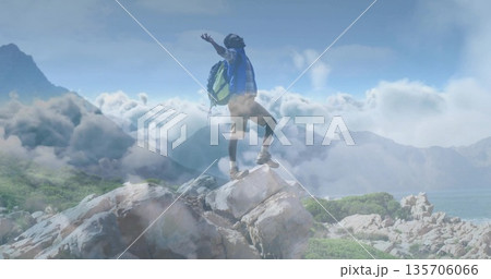 Standing hiker raising arms triumphantly on mountain summit, with rocky outcrop and green backpack Standing hiker raising arms triumphantly on mountain summit, with rocky outcrop and green backpack 135706066