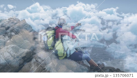 Taking selfie mature hiking couple leaning on coastal edge, with smartphone, backpacks and poles Taking selfie mature hiking couple leaning on coastal edge, with smartphone, backpacks and poles 135706071