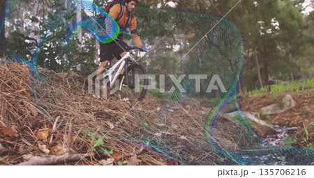 Riding man wearing orange jersey helmet and gloves down forest slope, with white bike, backpack 135706216