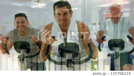 Three men in t-shirts cycling on stationary bikes in gym, with white towel, financial chart overlay 135706219