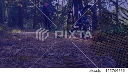 Two riders wearing hooded jacket and leggings cycling along pine forest trail, with bikes, backpack 135706286