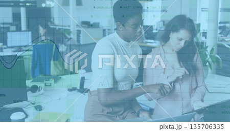 Collaborating female colleagues analyzing data on laptop at open office, with smartphone and plant 135706335