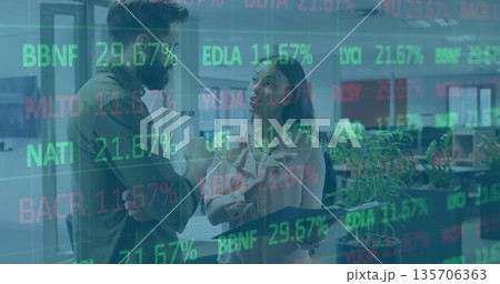 Discussing market trends colleagues in business attire holding tablet in office with stock overlays 135706363