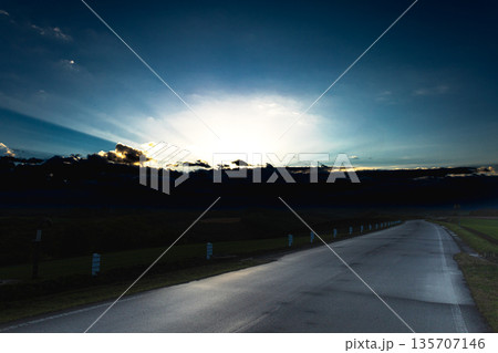 北海道美瑛町の丘の上から見た沈む太陽の光と真っ直ぐな道 135707146